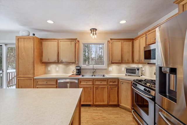 kitchen featuring backsplash, sink, light wood-type flooring, and appliances with stainless steel finishes