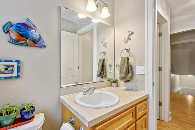 bathroom featuring wood-type flooring, vanity, and toilet