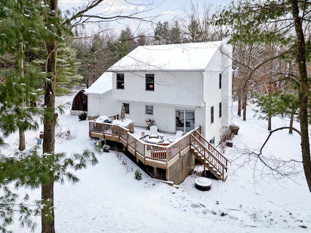 snow covered back of property with a deck