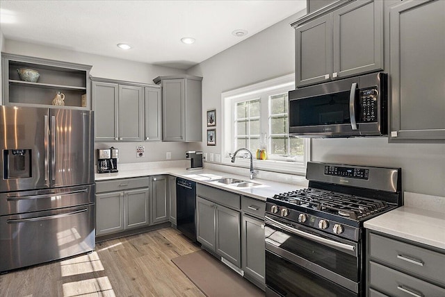 kitchen featuring appliances with stainless steel finishes, light hardwood / wood-style flooring, gray cabinetry, and sink