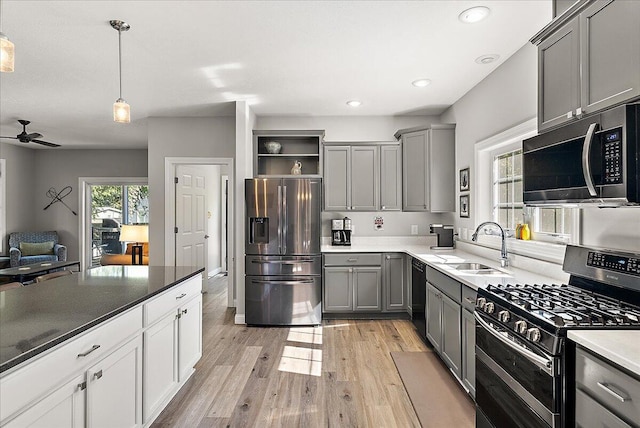 kitchen featuring gray cabinets, hanging light fixtures, light wood-type flooring, and appliances with stainless steel finishes