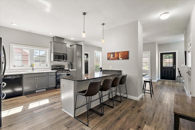 kitchen with a breakfast bar area, hanging light fixtures, stainless steel appliances, and light wood-type flooring