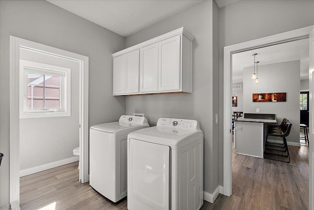 laundry area featuring light hardwood / wood-style flooring, cabinets, and independent washer and dryer