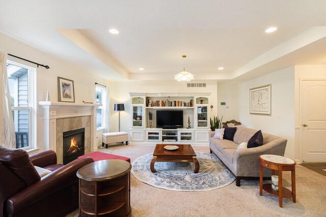 carpeted living room with a tray ceiling and a fireplace