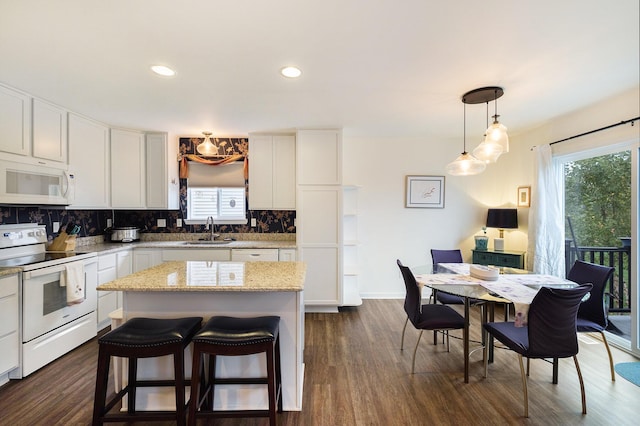 kitchen featuring white cabinets, a kitchen island, white appliances, and sink