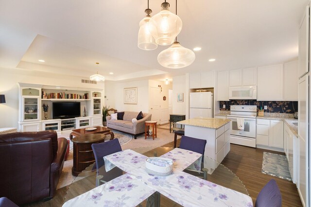 dining space featuring a raised ceiling and dark wood-type flooring