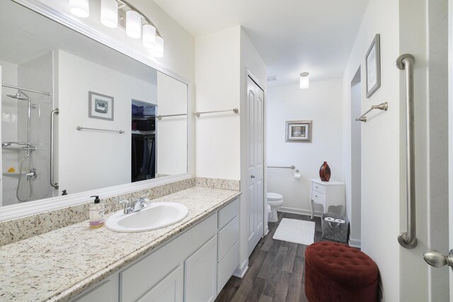 bathroom with wood-type flooring, vanity, toilet, and a shower with shower door