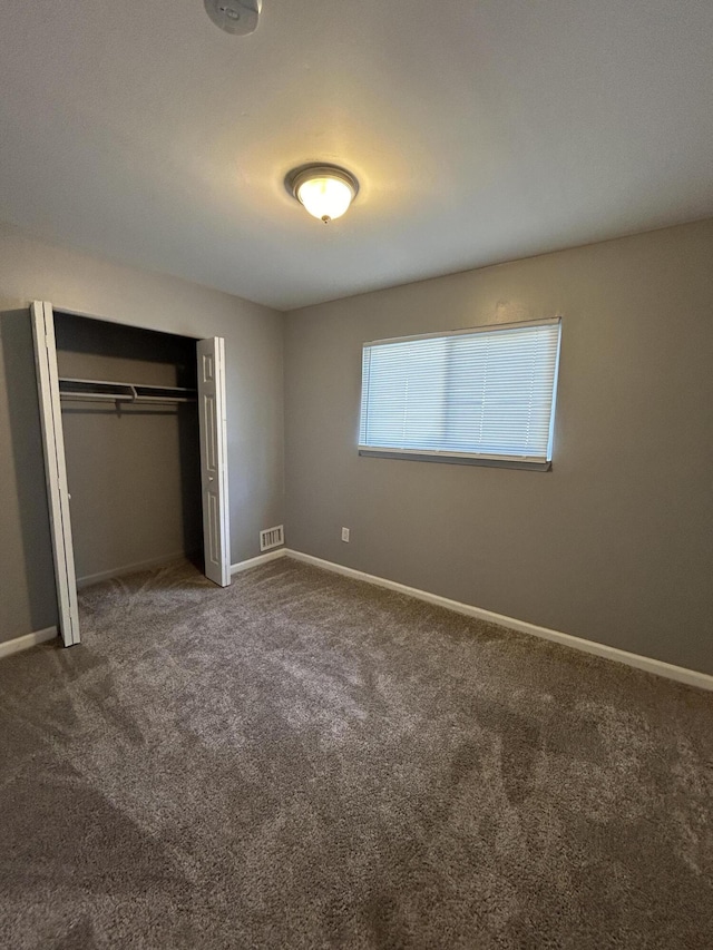 unfurnished bedroom featuring dark carpet and a closet