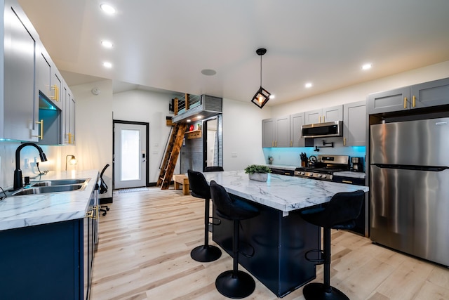 kitchen with light stone countertops, sink, decorative light fixtures, and appliances with stainless steel finishes