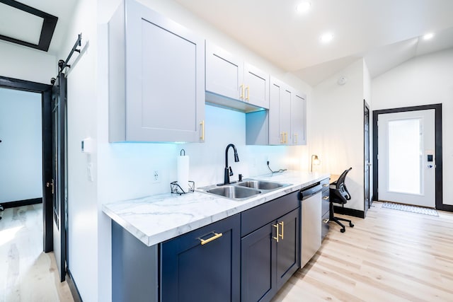 kitchen featuring dishwasher, white cabinets, sink, light hardwood / wood-style flooring, and a barn door