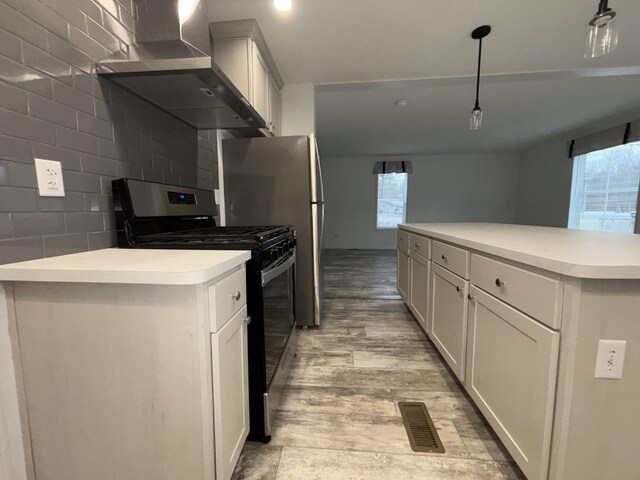 kitchen with black stove, wall chimney exhaust hood, pendant lighting, white cabinets, and a kitchen island