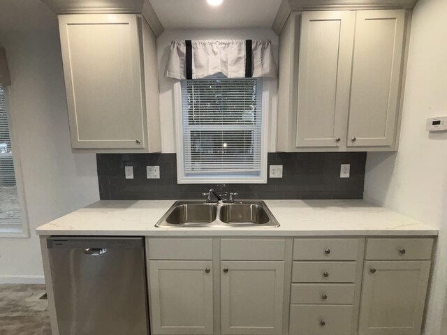 kitchen featuring decorative backsplash, light stone counters, sink, and stainless steel dishwasher