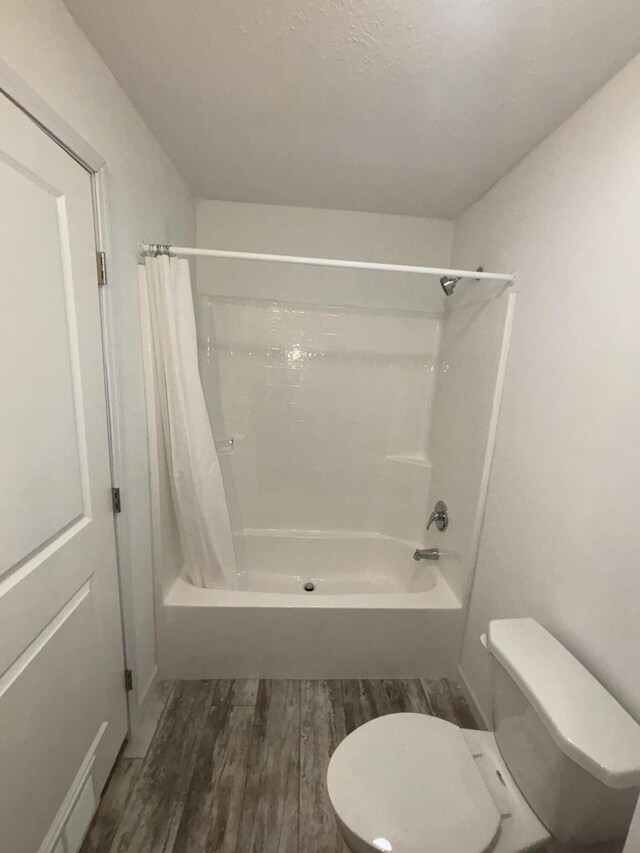 bathroom with hardwood / wood-style floors, toilet, and shower / tub combo