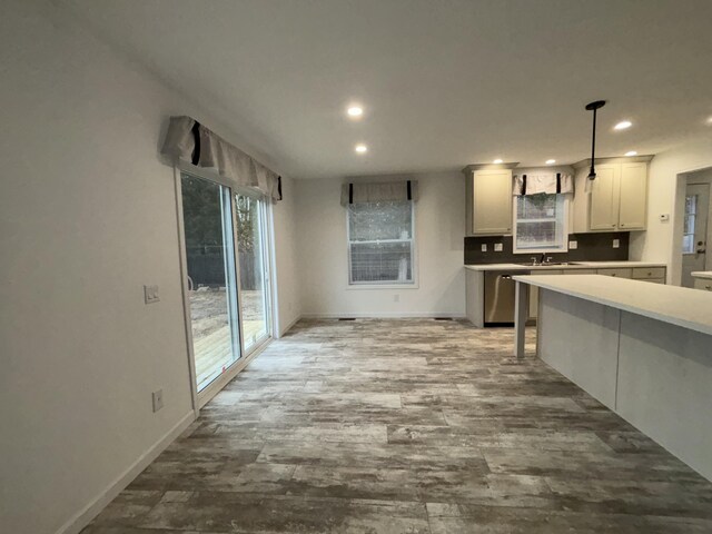 kitchen featuring tasteful backsplash, sink, dishwasher, light hardwood / wood-style floors, and hanging light fixtures