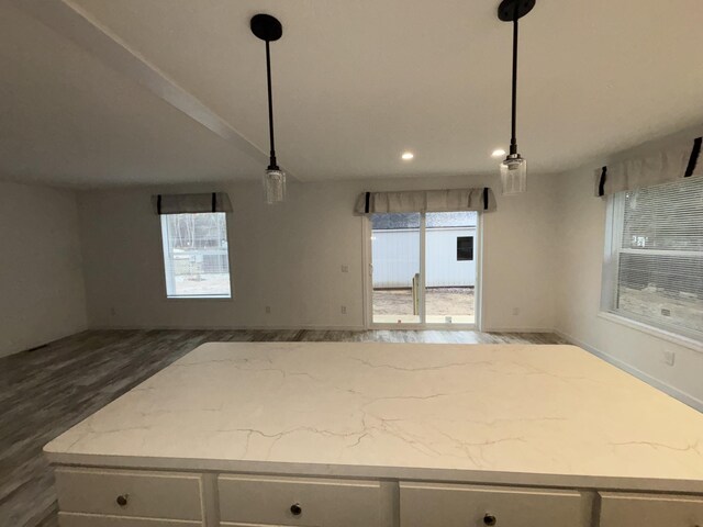 kitchen with white cabinets, pendant lighting, light stone countertops, and a healthy amount of sunlight