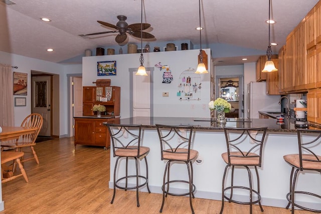 kitchen featuring ceiling fan, white fridge, decorative light fixtures, and lofted ceiling