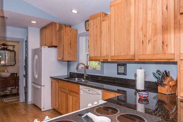 kitchen with dishwasher, lofted ceiling, sink, dark hardwood / wood-style floors, and dark stone countertops