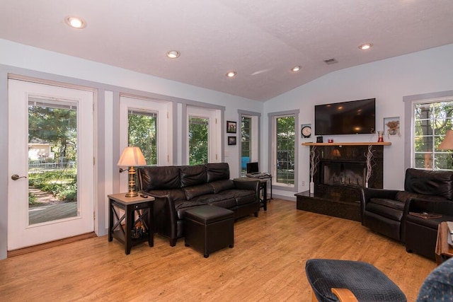 living room featuring light hardwood / wood-style flooring, a high end fireplace, and vaulted ceiling