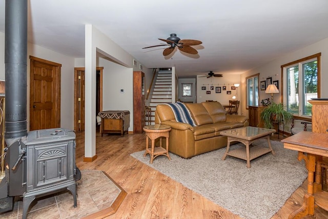 living room with ceiling fan, light hardwood / wood-style floors, and a wood stove