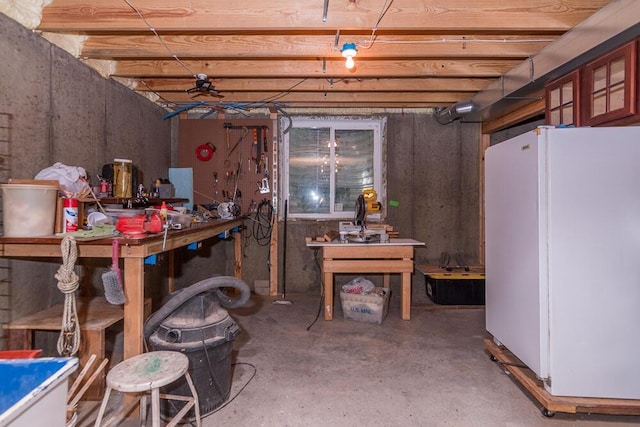 basement with a workshop area and white refrigerator