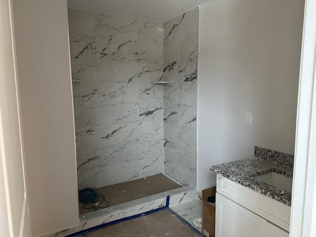 full bath featuring marble finish floor, a shower, and vanity