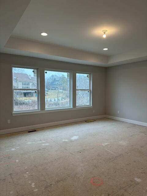 unfurnished room featuring baseboards, visible vents, a raised ceiling, and recessed lighting