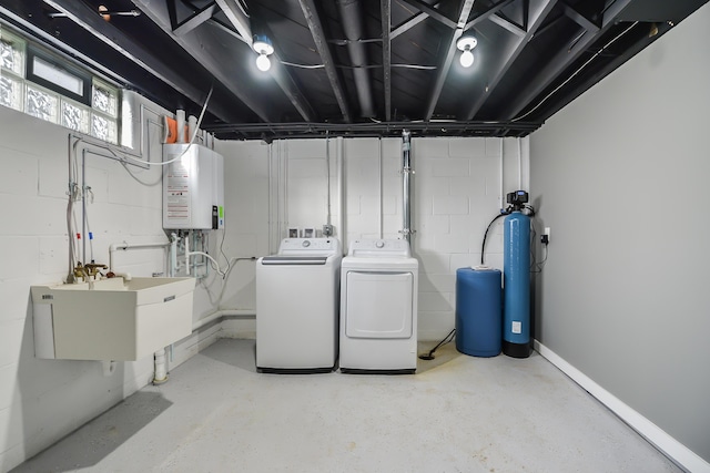 clothes washing area with washer and clothes dryer, tankless water heater, and sink