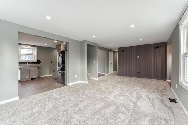 unfurnished living room with sink and light colored carpet