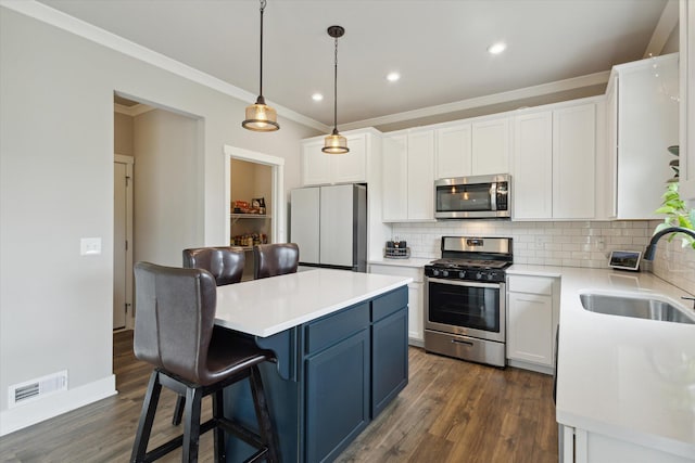 kitchen with appliances with stainless steel finishes, backsplash, sink, white cabinetry, and hanging light fixtures