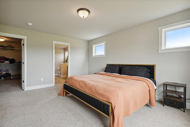 carpeted bedroom with a closet, ensuite bath, and a spacious closet