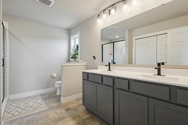 bathroom featuring vanity, toilet, wood-type flooring, and walk in shower