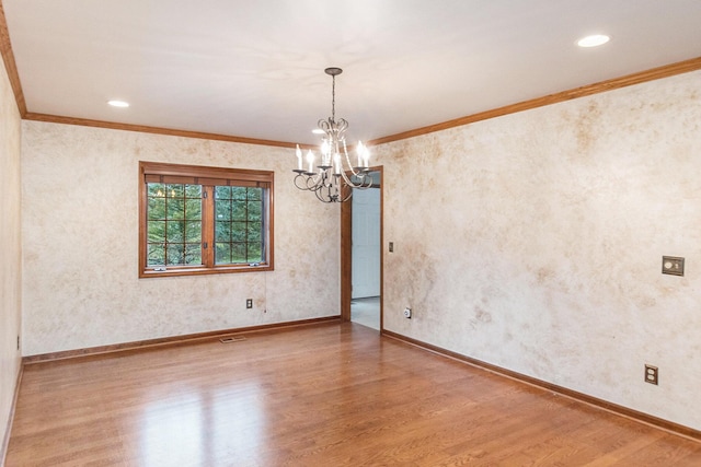 empty room featuring hardwood / wood-style floors, an inviting chandelier, and crown molding