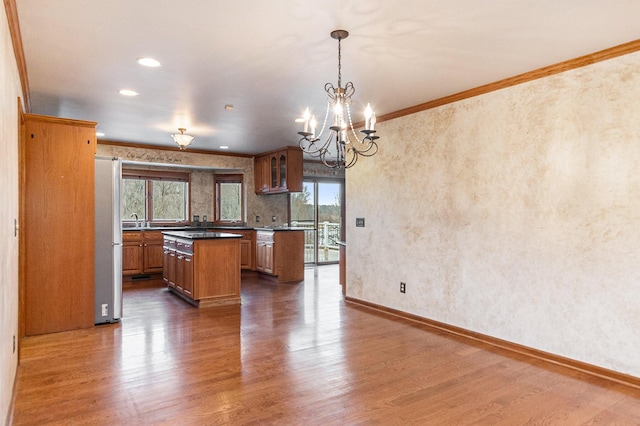 kitchen with pendant lighting, a center island, crown molding, dark hardwood / wood-style floors, and stainless steel refrigerator