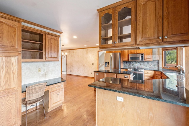 kitchen featuring sink, light wood-type flooring, ornamental molding, kitchen peninsula, and stainless steel appliances