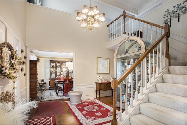 foyer entrance featuring crown molding, a chandelier, a high ceiling, and hardwood / wood-style flooring