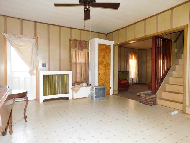 living room featuring ceiling fan, crown molding, and wooden walls