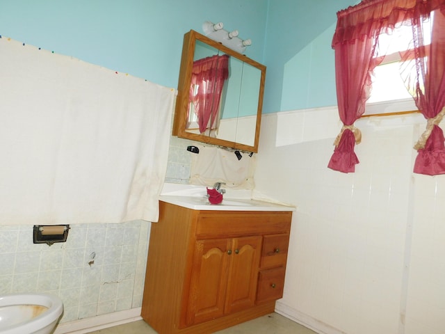 bathroom featuring vanity, tile walls, and toilet