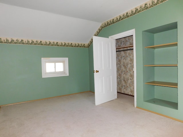 unfurnished bedroom with light colored carpet, vaulted ceiling, and a closet