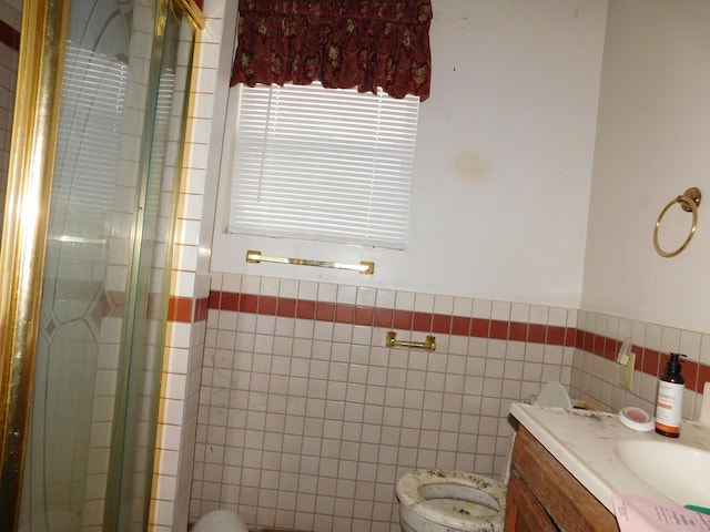 bathroom featuring vanity, toilet, an enclosed shower, and tile walls