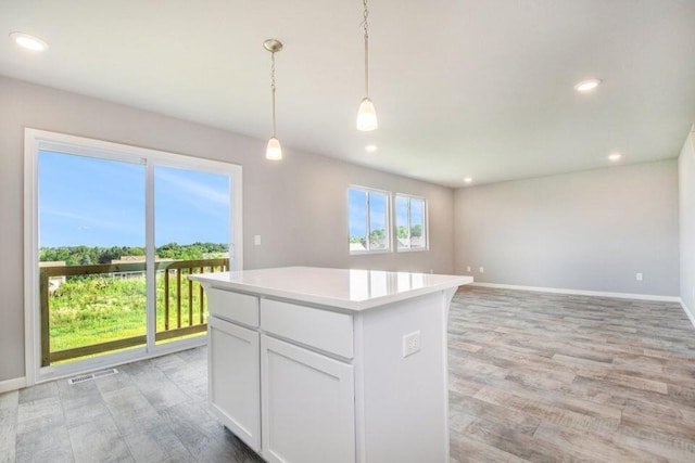 kitchen featuring a center island, white cabinets, light hardwood / wood-style floors, and decorative light fixtures