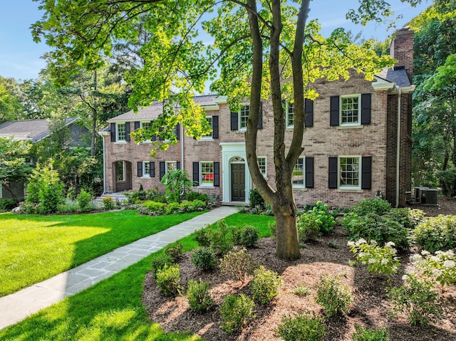 colonial inspired home featuring cooling unit and a front lawn