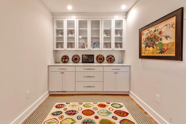 bar featuring decorative backsplash and white cabinetry