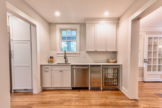 bar featuring white cabinets, sink, dishwasher, light hardwood / wood-style floors, and wine cooler