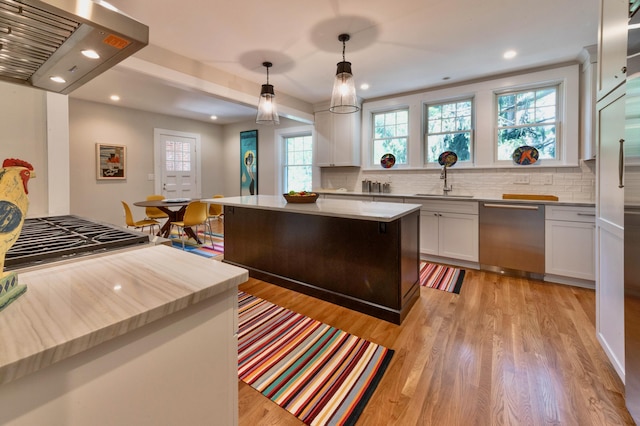 kitchen featuring island range hood, white cabinets, hanging light fixtures, a kitchen island, and stainless steel appliances