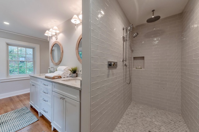 bathroom featuring wood-type flooring, vanity, and a tile shower