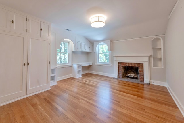 unfurnished living room featuring a fireplace, light wood-type flooring, built in features, and vaulted ceiling