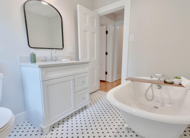 bathroom featuring tile patterned flooring, vanity, toilet, and a tub