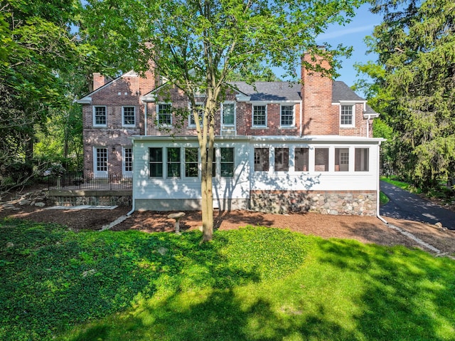 rear view of property with a sunroom and a lawn