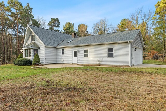 rear view of property featuring a yard and a garage