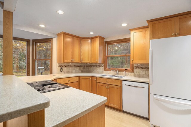 kitchen with decorative backsplash, white appliances, kitchen peninsula, and sink